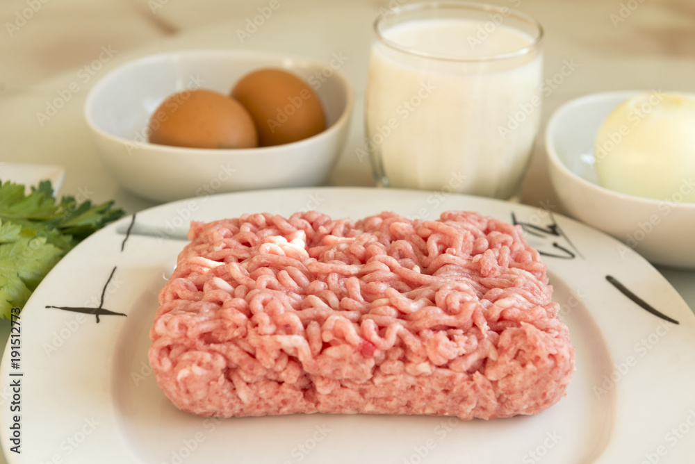 pork minced meat on a plate, ingredients for cooking meat cutlets, 2 eggs, a glass of milk, onion, food