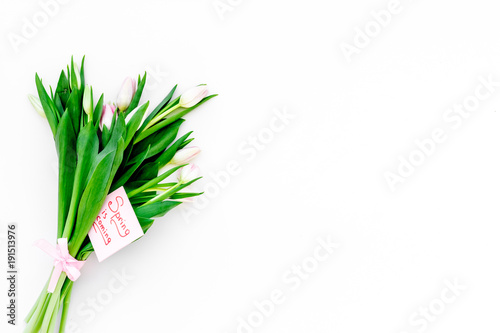 Spring mood. Tulips near Spring is coming hand lettering on white background top view copy space