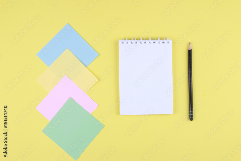 Notebook on office table with a cup of coffee, plant, stationery and office supplies. Blank notepad paper for input copy or text. Top view desk, flat lay yellow color background concept. Notebook on office table with a cup of coffee, plant, stationery and office supplies. Blank notepad paper for input copy or text. Top view desk, flat lay yellow color background concept.