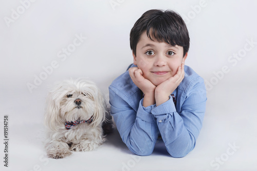niño tumbado junto a su perro sobre fondo blanco