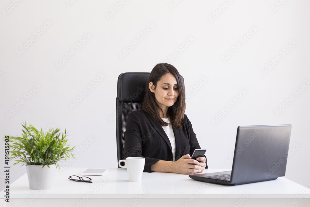 beautiful young Business woman working in the office, using her laptop and mobile phone. Business Concept.white backgrounds. Indoors beautiful young Business woman working in the office, using her laptop and mobile phone. Business Concept.white backgrounds. Indoors