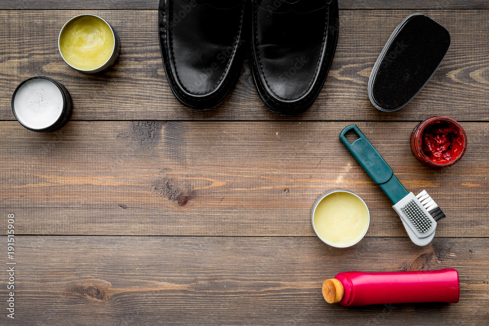 Shoe polish, brushes, wax near black shiny leather shoes on dark wooden background top view copy space Shoe polish, brushes, wax near black shiny leather shoes on dark wooden background top view copy space