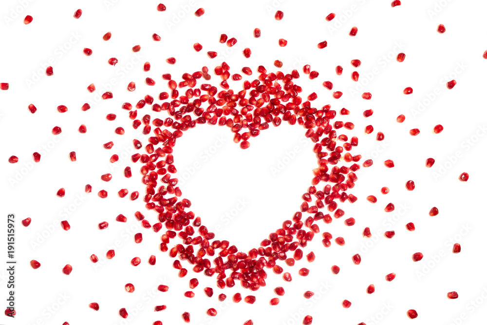 Pomegranate seeds in heart shape, white background, copyspace Pomegranate seeds in heart shape, white background, copyspace