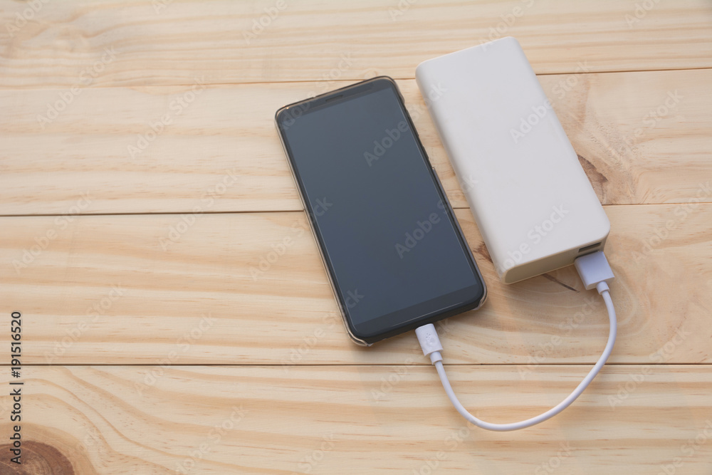 Mobile smart phones charging with power bank on desk and copy space. Mobile smart phones charging with power bank on desk and copy space.