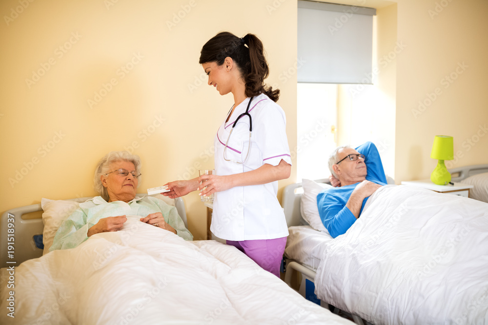 Nurse at nursing home brings medicine to senior immobile woman Nurse at nursing home brings medicine to senior immobile woman