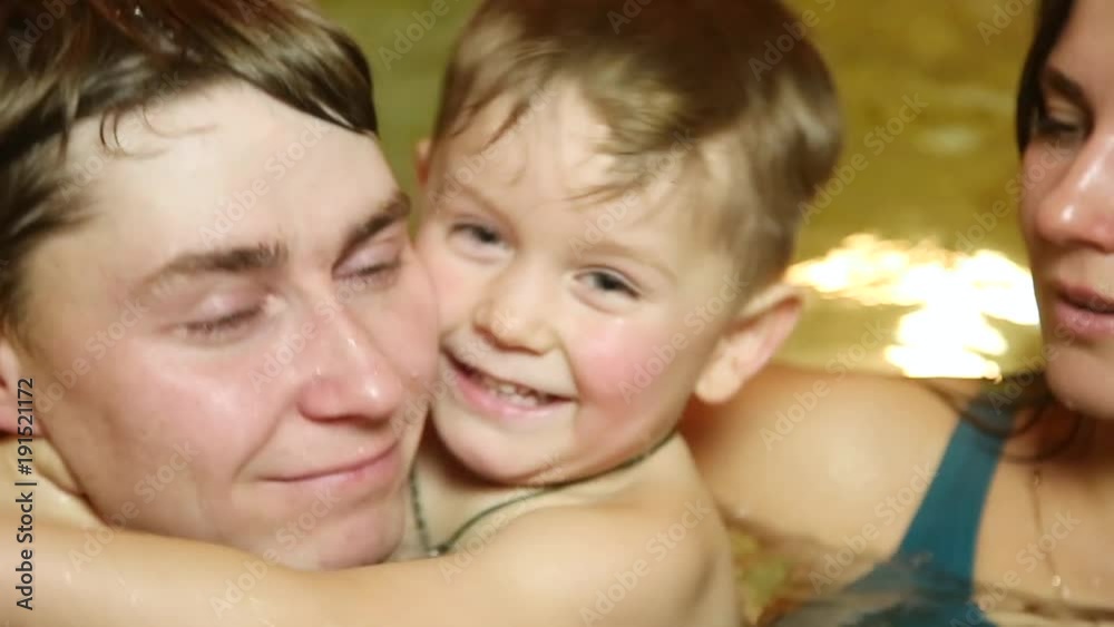 happy beautiful family with a small child swimming in the pool happy beautiful family with a small child swimming in the pool