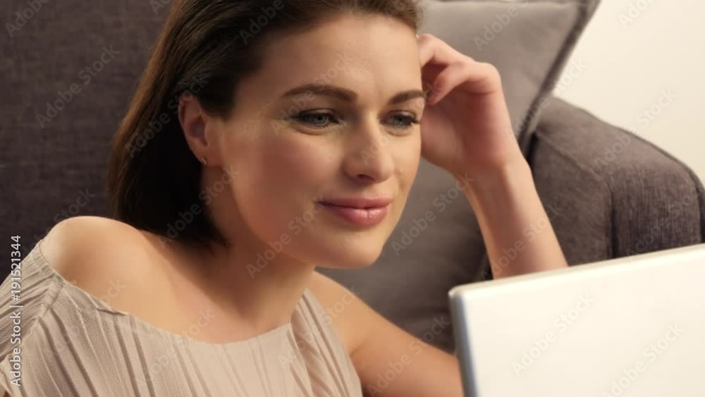 brunette woman with laptop on a sofa smiling brunette woman with laptop on a sofa smiling
