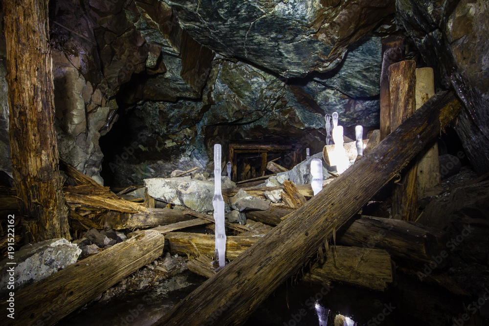 Underground abandoned ore mine shaft tunnel gallery with ice stalactites and stalagmites