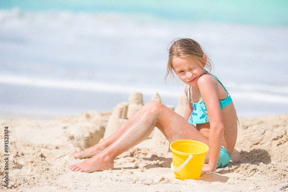 Adorable little girl playing with beach toys on white tropial beach