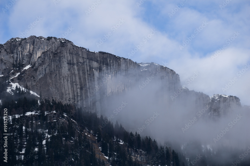 Obraz premium Vertical stone wall engulfed in clouds in the mountains of Austria