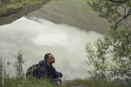 Retrato de hombre joven junto al lago Diamond en Nueva Zelanda en un día gris lleno de nubes.
