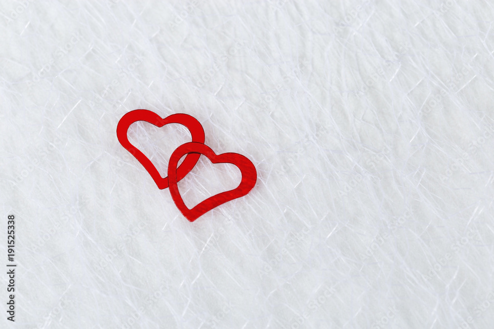 Two bright red hearts on a white blurred translucent fabric. Greeting card, background or invitation with copy space for text. Flat lay.