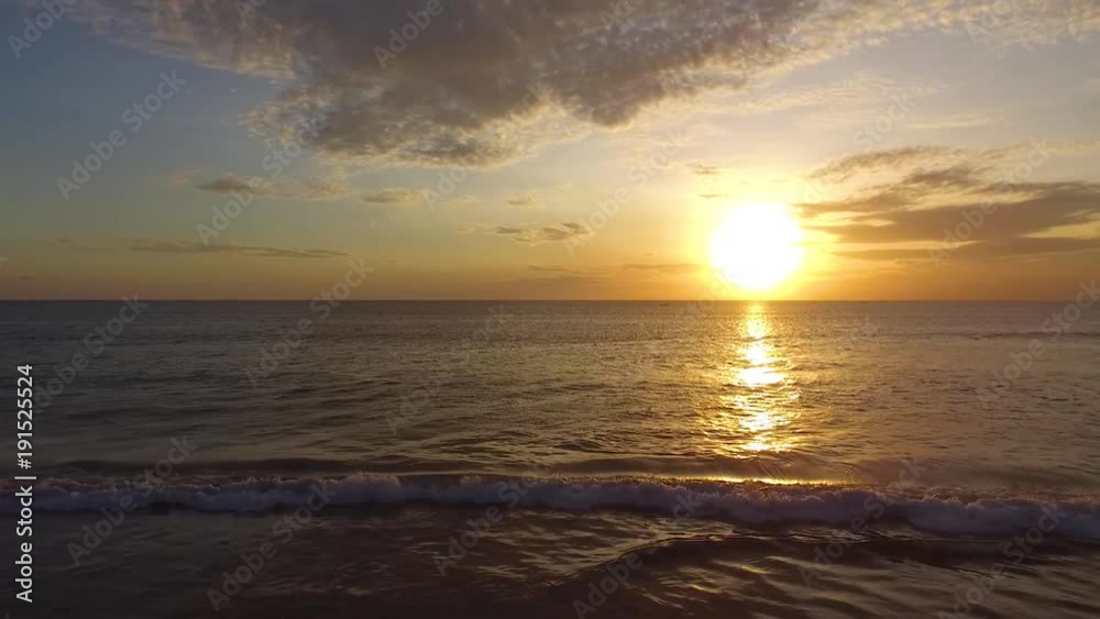 Gliding drone shot of the sunset over a peaceful beach and serene ocean Gliding drone shot of the sunset over a peaceful beach and serene ocean