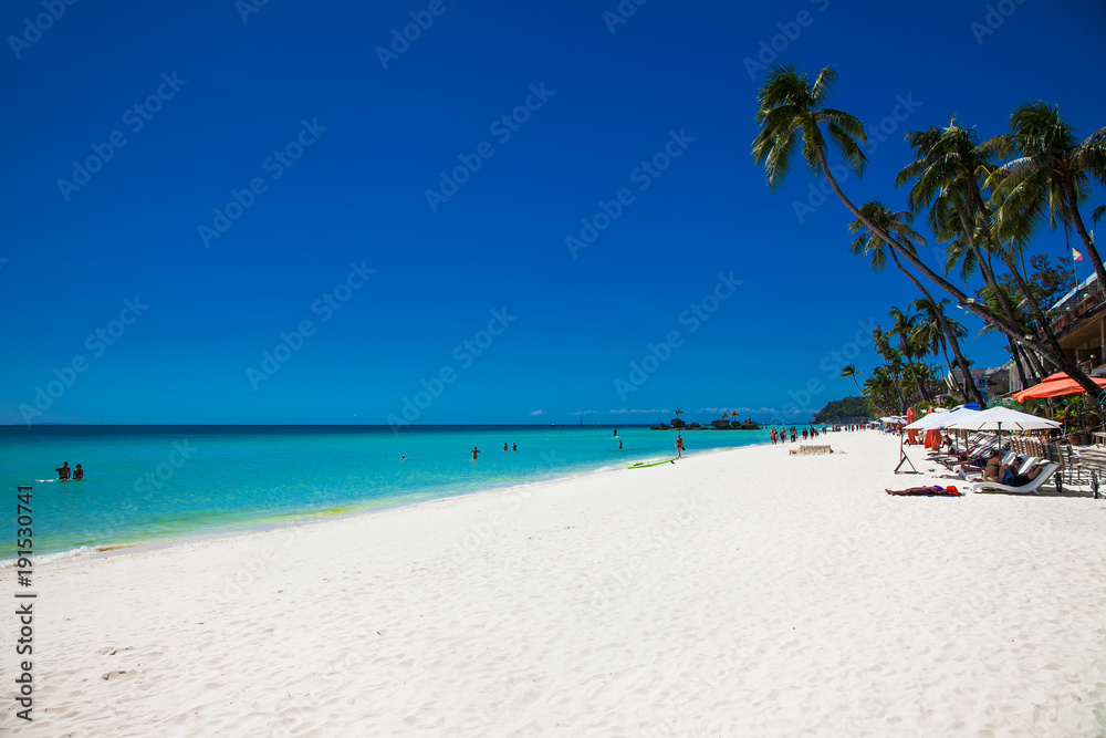 Tropical vacation , sun, blue sky and palm tree on White beach at Boracay, Philippines.