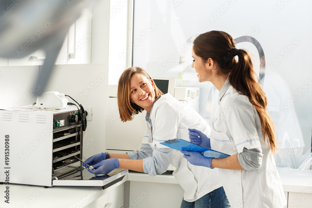 Female dentists in dental office .They cleans equipment for next working day.Using autoclave. Female dentists in dental office .They cleans equipment for next working day.Using autoclave.