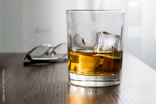 Glass of whiskey, brandy, cognac with ice cubes on wooden table desk with glassess. Mockup of product, gift for man