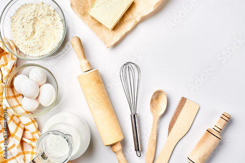 Preparation of the dough. A measurement of the amount of ingredients in the recipe. Ingredients for the dough: flour, eggs, rolling pin, whisk, milk, butter, cream. Top view, space for text