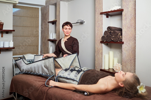 Photos A woman lying down doing pressotherapy treatment in a spa center.