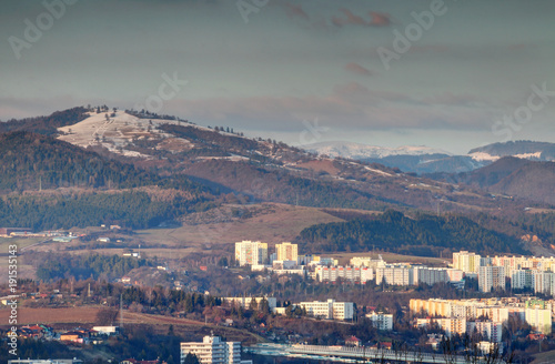 Sunlit Selciansky diel and Zvolen peaks of Starohorske and Velka Fatra mountains over colorful socialist tower block housing estate in Banska Bystrica outskirts in winter Carpathians Slovakia Europe
