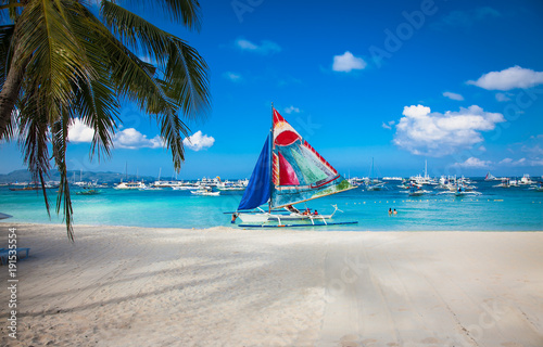 Philippine traditional boat with blue sail on White Beach. Boracay, Philippines.