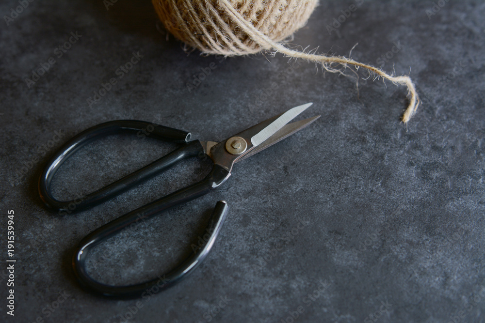 Scissors with rough twine on a grey tile background