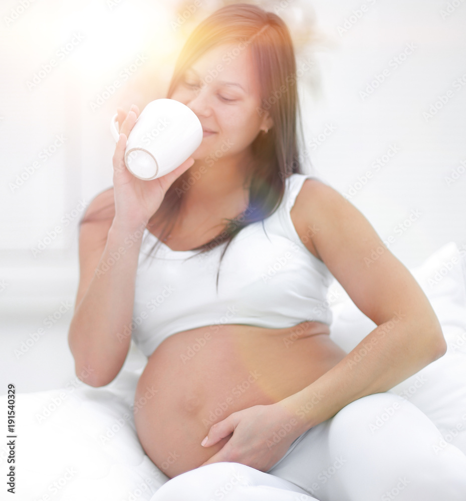 happy pregnant woman drinking milk sitting in the living room. happy pregnant woman drinking milk sitting in the living room.
