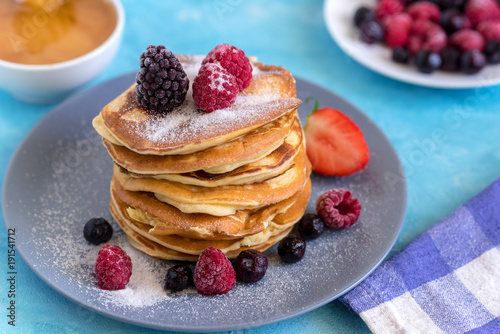 Fluffy and delicate pancakes with powdered sugar and berries.