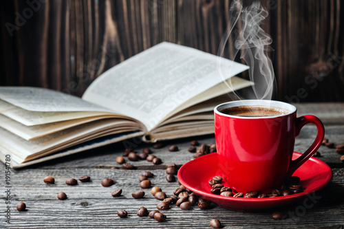 Red cup of coffee and books opened diary on wooden table with coffee beans