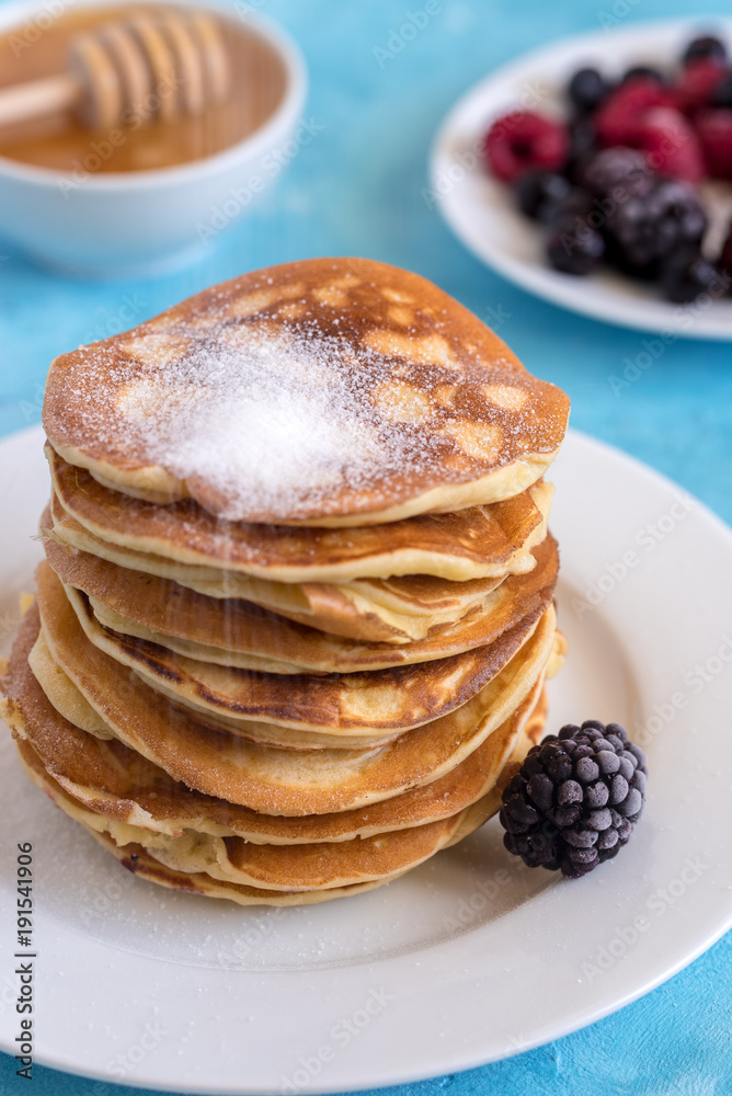 Fluffy and delicate pancakes with powdered sugar and berries. Fluffy and delicate pancakes with powdered sugar and berries.