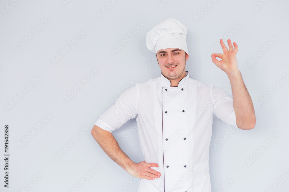 Young chef cook shows ok on a white background. Young chef cook shows ok on a white background.