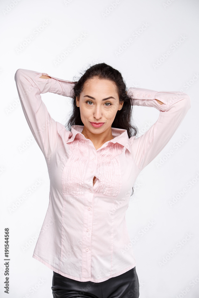 Portrait of a beautiful brunette girl with dark skin in a pink shirt, with a serious expression. Emotion view is arrogant with high. Businesswoman porter without a smile on a white background Portrait of a beautiful brunette girl with dark skin in a pink shirt, with a serious expression. Emotion view is arrogant with high. Businesswoman porter without a smile on a white background
