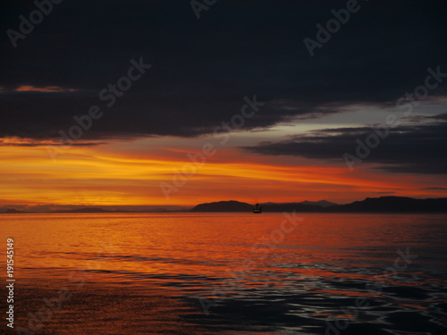 Fototapeta Naklejka Na Ścianę i Meble -  Beautiful orange sunset in Alaska waters - amazing contrast with sunset and clounds