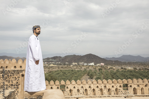 arab man in traditional omani outfit overlooking the view of Omani countryside photo