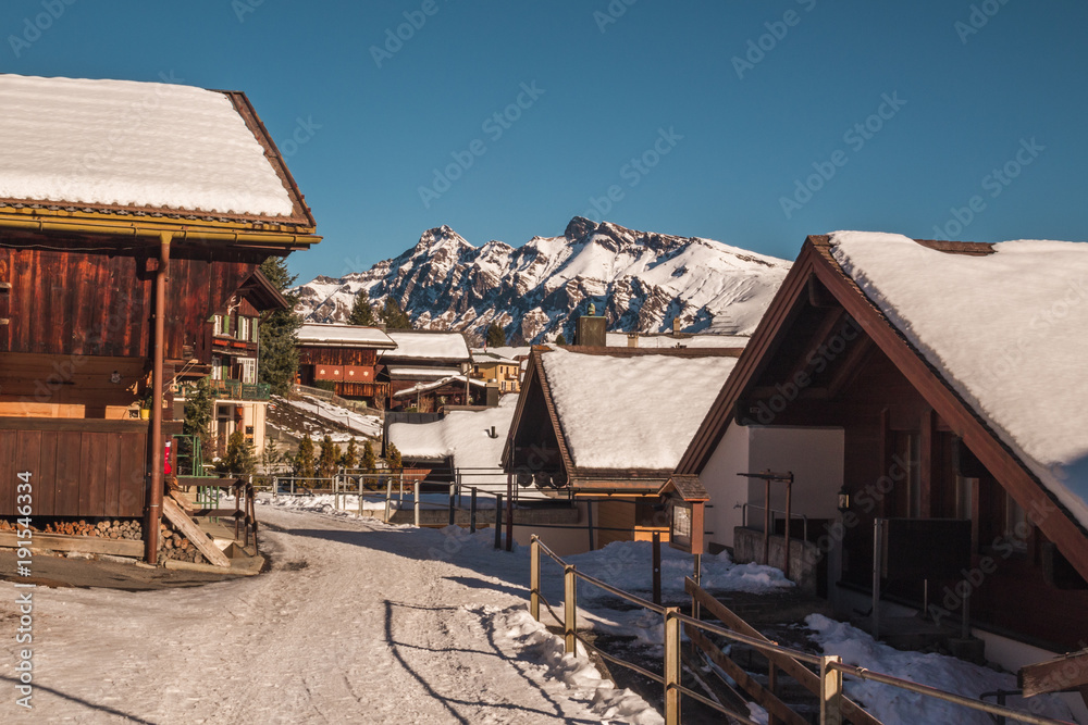 Alpine town street with snow covered mountains in the background, Switzerland