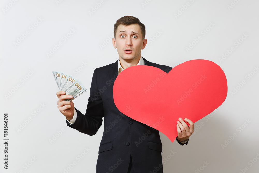 Dissatisfied man with big red heart, bundle of cash money dollars isolated on white background. Copy space for advertisement. St. Valentine's Day, International Women's Day, birthday holiday concept. Dissatisfied man with big red heart, bundle of cash money dollars isolated on white background. Copy space for advertisement. St. Valentine's Day, International Women's Day, birthday holiday concept.