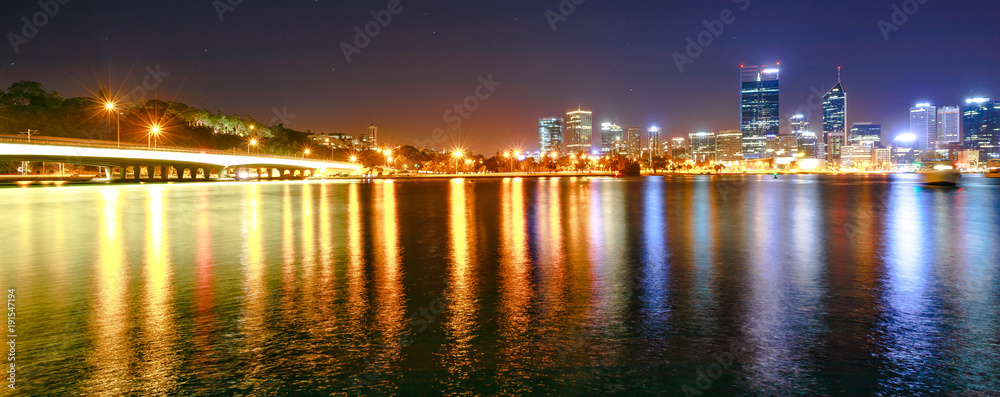 Panorama of Narrows Bridge and Perth Skyline illuminated at night. Perth Downtown cityscape with skyscrapers reflecting on the Swan River from Mill point, Western Australia.