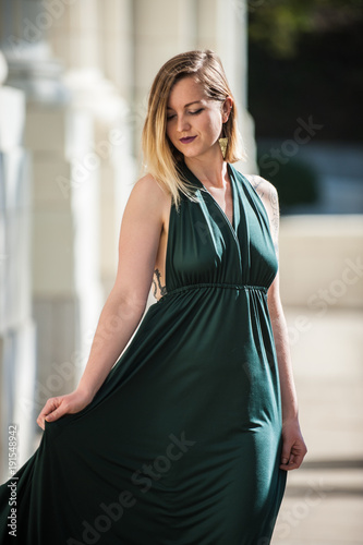 Emerald Green halter top dress looks beautiful on dreamy blonde model on concrete walk.