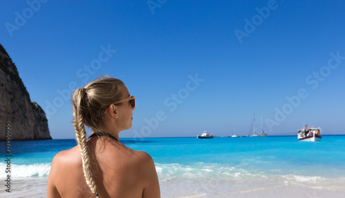 Junge blonde Frau an einem Strand mit türkisblauem Wasser © weixx