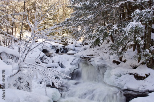 Beautiful winter waterfall in the white snowy forest 