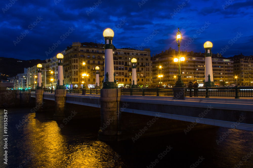 Historic Zurriola Bridge over Urumea river under dark blue sky at twilight in the city of San Sebastian, Spain