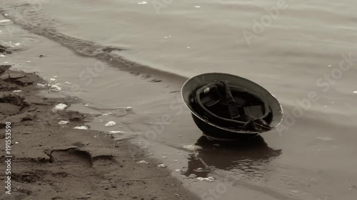 Footage of world war era brodie soldier helmet on beach.