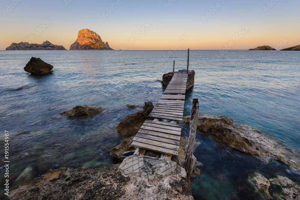 Small wooden pier in Cala d'Hort beach, Es Vedra as background, Ibiza island, Spain