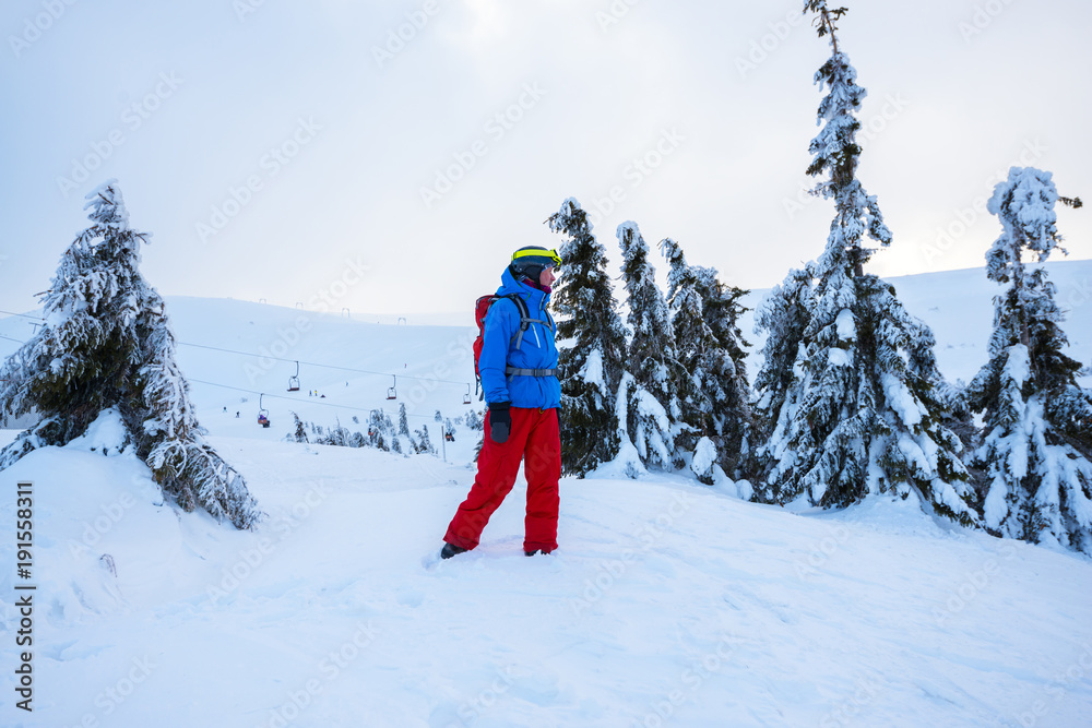 Snowboarder relaxes on a mountain ridge at sunny evening