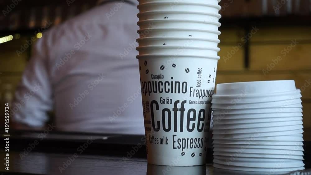 Coffee 2 go cups on a counter in front of a barista