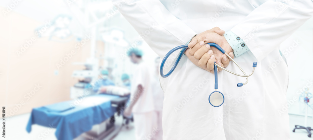 Doctor man with stethoscope and surgeons team   in operating room in modern hospital ,Blurred background , Medical technology and healthcare concept