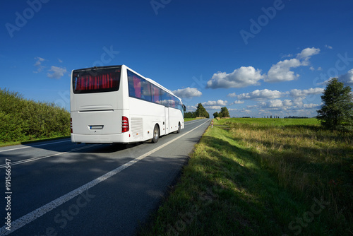 Obraz na płótnie White bus traveling on asphalt road in landscape on a sunny day with blue sky and white clouds w salonie