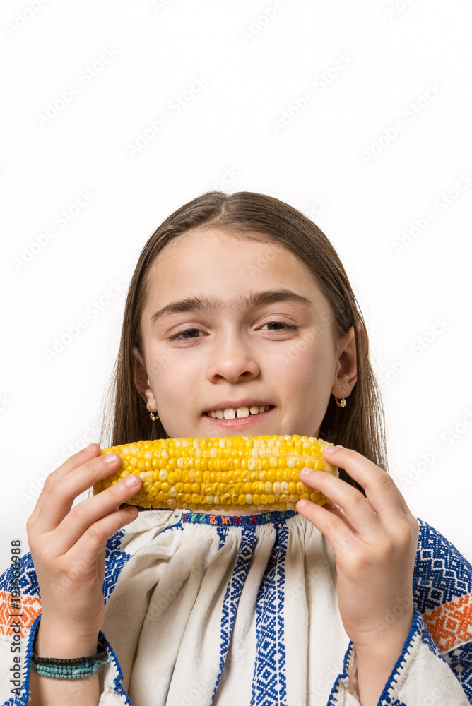 Indoor close up portrait of a smiling young girl getting ready to eat a corn cob. Indoor close up portrait of a smiling young girl getting ready to eat a corn cob.
