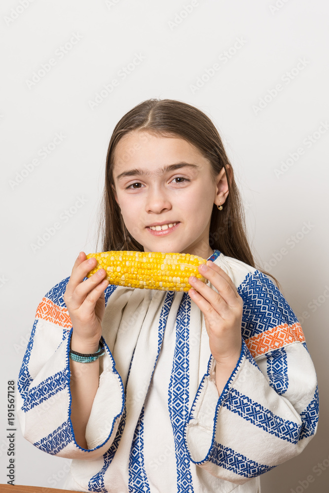 Indoor close up portrait of a smiling young girl getting ready to eat a corn cob. Indoor close up portrait of a smiling young girl getting ready to eat a corn cob.