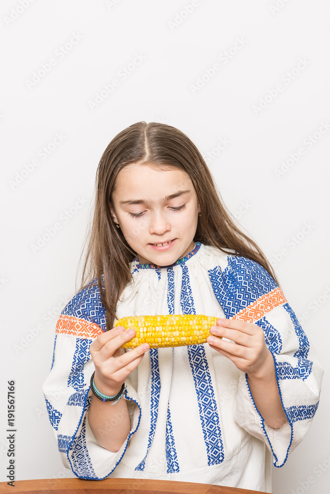 Indoor close up portrait of a smiling young girl getting ready to eat a corn cob. Indoor close up portrait of a smiling young girl getting ready to eat a corn cob.