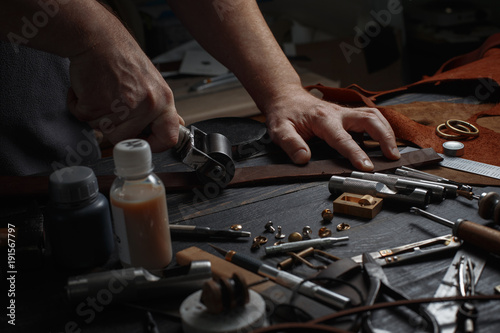 Man working with leather using crafting DIY tools.